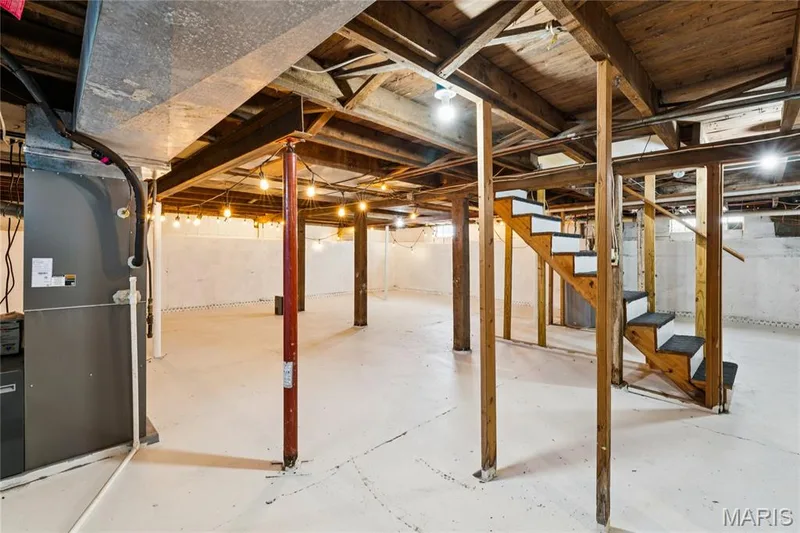 Unfinished lower level with wood support beams, exposed ceiling joists, and a built-in wooden staircase with dark risers — 435 Highway T, Foristell, MO 63348