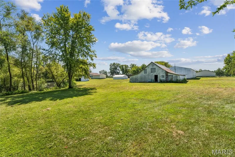 Expansive grassy area with mature trees, a visible water feature, and multiple outbuildings — 435 Highway T, Foristell, MO 63348