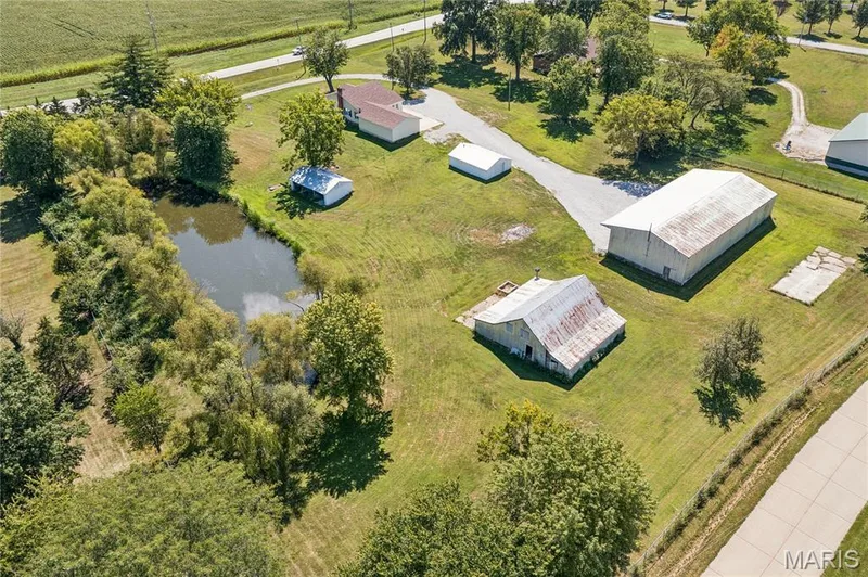 Expansive grounds featuring a private pond, multiple outbuildings, gravel driveways, and mature trees — 435 Highway T, Foristell, MO 63348