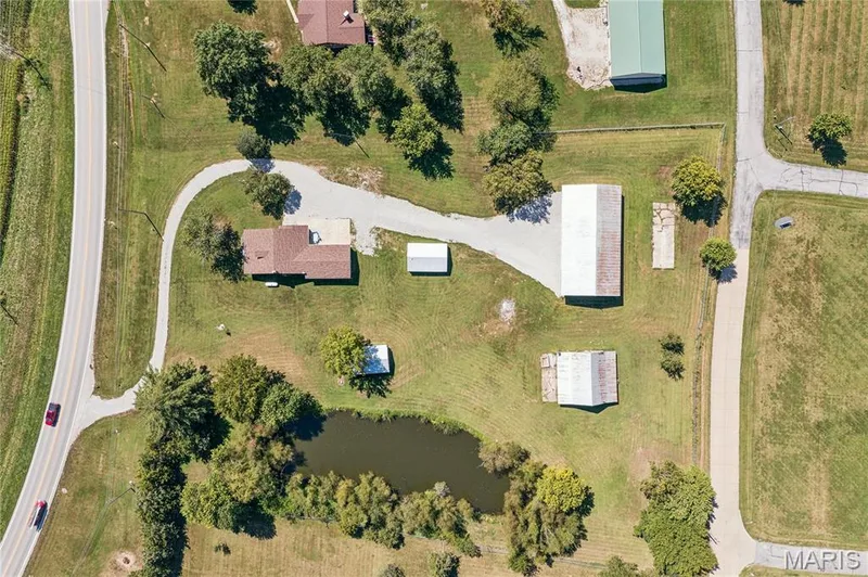 Expansive lot featuring a private pond, multiple outbuildings, and a gravel driveway — 435 Highway T, Foristell, MO 63348