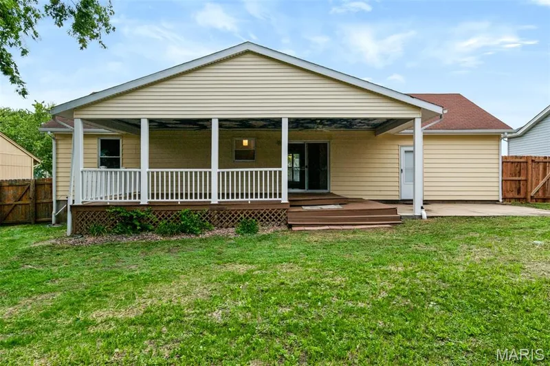 Covered deck with white railing, sliding glass door access, and a concrete patio — 1314 Warrior Song Way, O'Fallon, MO 63366