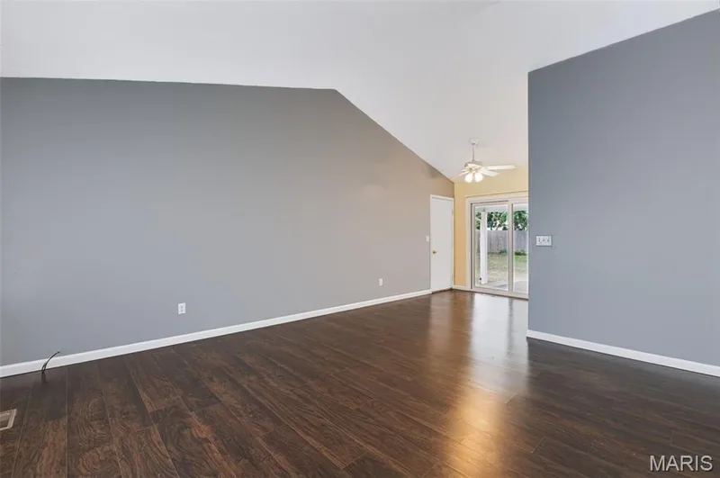 Vaulted ceiling with a ceiling fan, dark wood-finish flooring, and sliding glass doors to the exterior — 1314 Warrior Song Way, O'Fallon, MO 63366