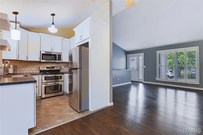 Kitchen featuring white cabinetry, stainless steel appliances, and a tile backsplash — 1314 Warrior Song Way, O'Fallon, MO 63366