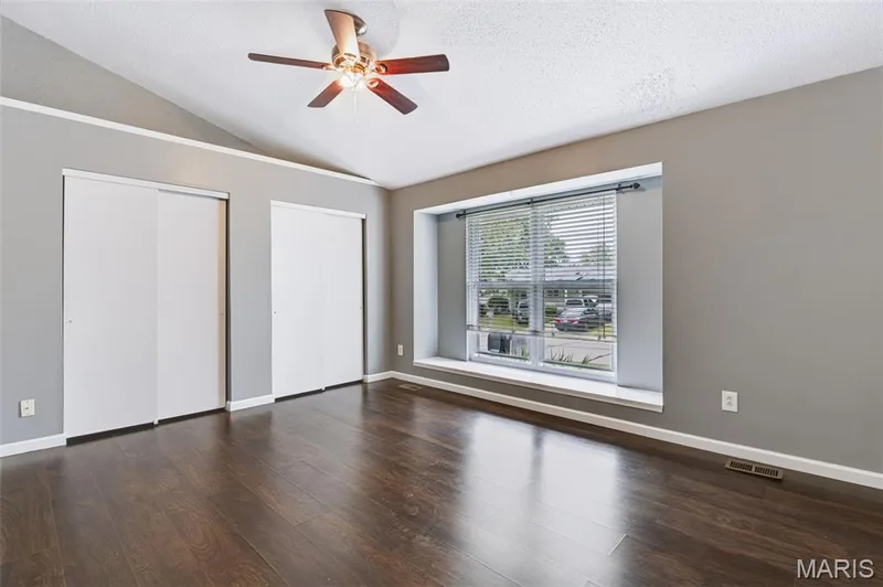 Vaulted ceiling with a ceiling fan, wood-finish flooring, and a window with blinds — 1314 Warrior Song Way, O'Fallon, MO 63366