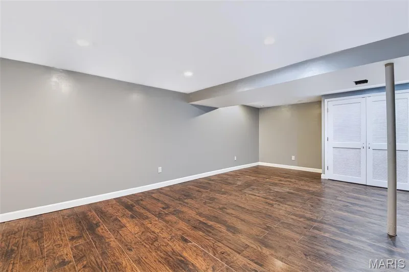 Recessed lighting illuminates the expansive room featuring wood-finish flooring and two-tone wall paint — 1314 Warrior Song Way, O'Fallon, MO 63366