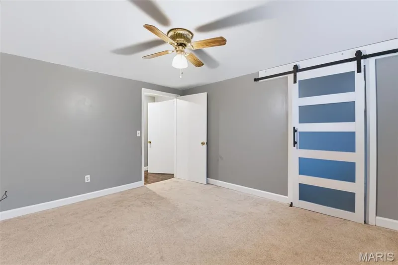 Light beige carpeting, soft gray wall paint, white trim, and a ceiling fan with brass accents — 1314 Warrior Song Way, O'Fallon, MO 63366