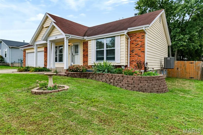 Exterior featuring brick accents, horizontal siding, and a two-car garage — 1314 Warrior Song Way, O'Fallon, MO 63366
