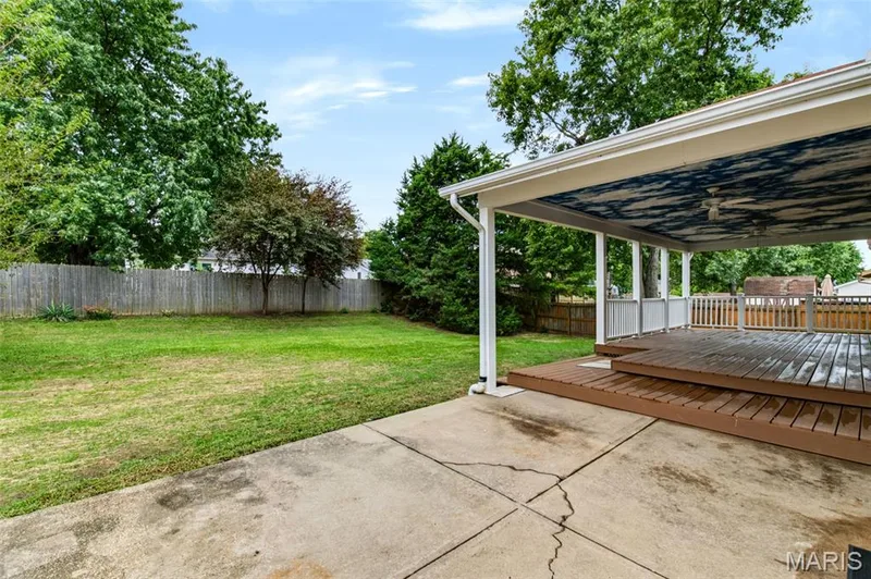 Expansive backyard featuring a manicured lawn, wood fencing, and mature trees — 1314 Warrior Song Way, O'Fallon, MO 63366