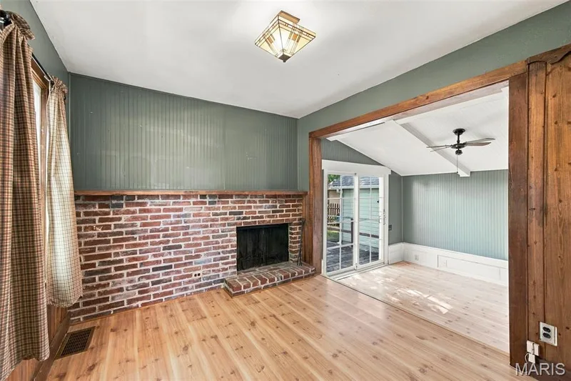 Back family Room features a cozy fireplace and steps down into a bright sunroom — 201 Perry Street, St Charles, MO 63301