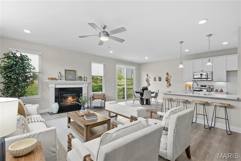 Open-concept living space featuring a fireplace with a white mantel, wood-finish flooring, recessed lighting, and a modern kitchen with a breakfast bar — 89 Alta Mira Court, Dardenne Prairie, MO 63368