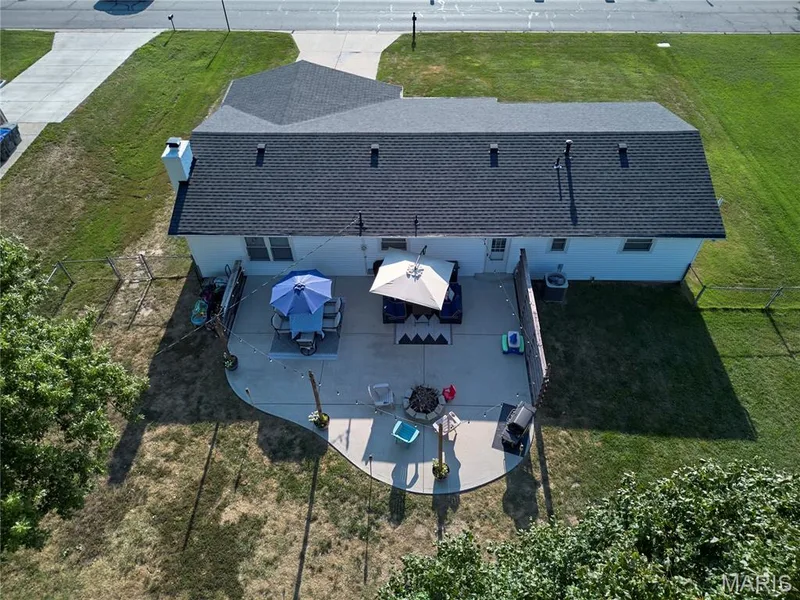 Asphalt shingle roof, chimney, concrete patio, fenced yard, and direct access to a paved road — 415 Westridge Drive, O'Fallon, MO 63366