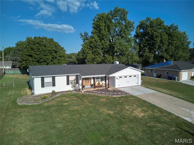 White exterior with dark shutters, attached garage, covered front porch, and established landscaping — 415 Westridge Drive, O'Fallon, MO 63366