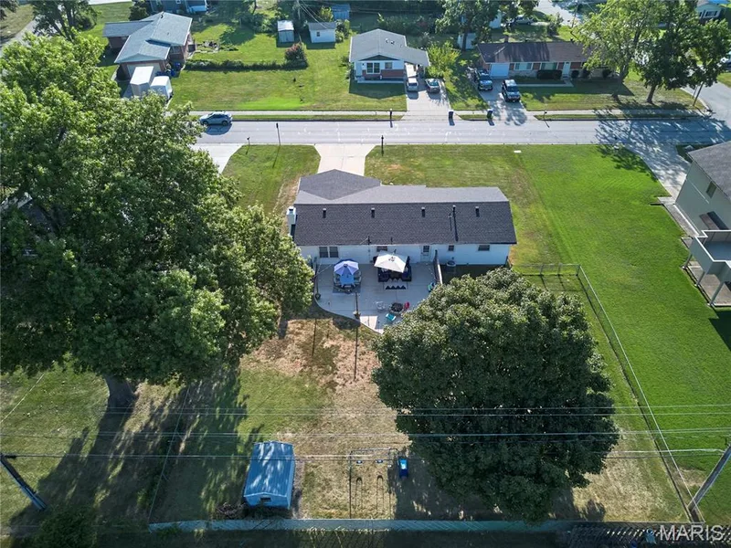 Rear exterior featuring a patio, mature trees, and a fence — 415 Westridge Drive, O'Fallon, MO 63366