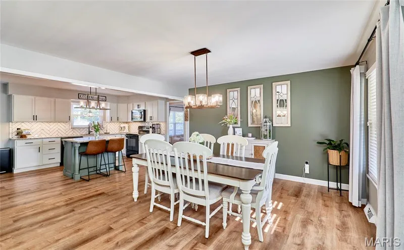 Open-concept living space with wood-finish flooring, a kitchen island, pendant lighting, and full-height cabinetry — 415 Westridge Drive, O'Fallon, MO 63366