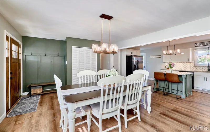 Open-concept living space featuring wood-finish flooring, a contemporary dining chandelier, and a kitchen island with seating — 415 Westridge Drive, O'Fallon, MO 63366