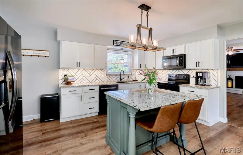 White shaker-style cabinetry with black hardware, herringbone tile backsplash, and wood-finish flooring — 415 Westridge Drive, O'Fallon, MO 63366