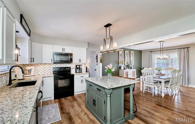 Kitchen featuring granite countertops, white cabinetry, a herringbone tile backsplash, and wood-finish flooring — 415 Westridge Drive, O'Fallon, MO 63366