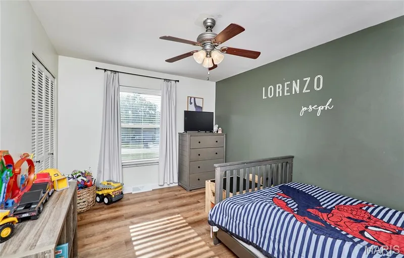 Wood-finish flooring, single window with blinds, ceiling fan with integrated lighting, and a bi-fold closet door — 415 Westridge Drive, O'Fallon, MO 63366