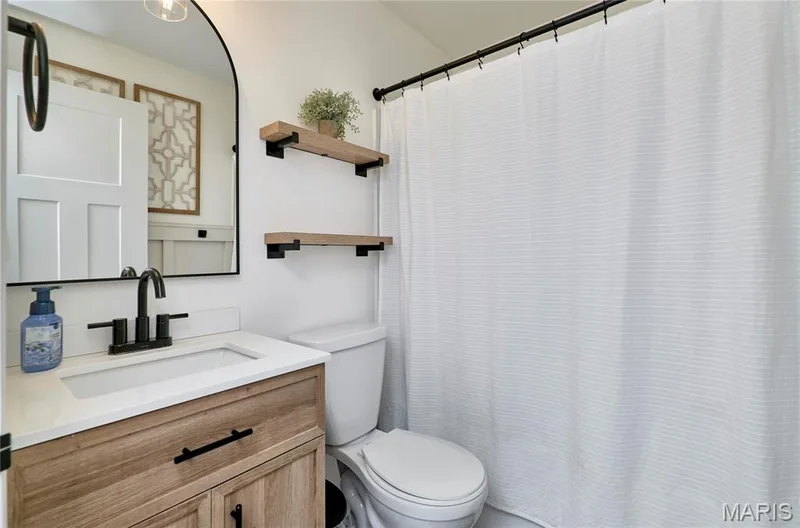 Wood-finish vanity with white countertop, undermount sink, and matte black faucet — 415 Westridge Drive, O'Fallon, MO 63366