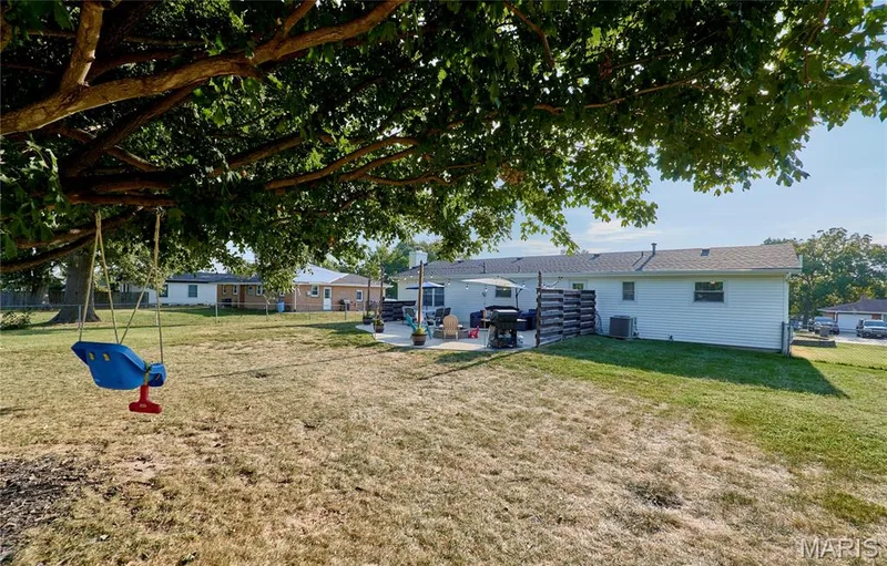 Expansive outdoor space featuring a large concrete patio, mature trees, and a spacious lawn — 415 Westridge Drive, O'Fallon, MO 63366