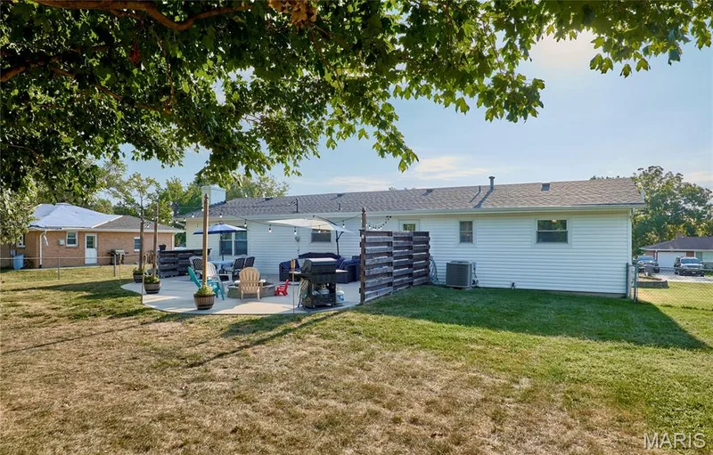 Expansive backyard featuring a concrete patio, white vinyl siding, and a partial privacy screen — 415 Westridge Drive, O'Fallon, MO 63366
