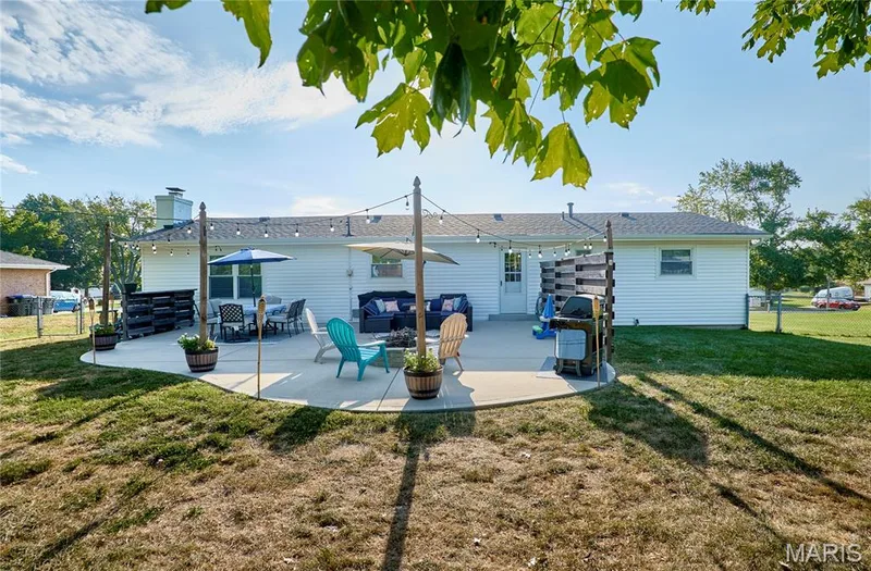 Expansive concrete patio with string lighting and a white vinyl-sided exterior — 415 Westridge Drive, O'Fallon, MO 63366