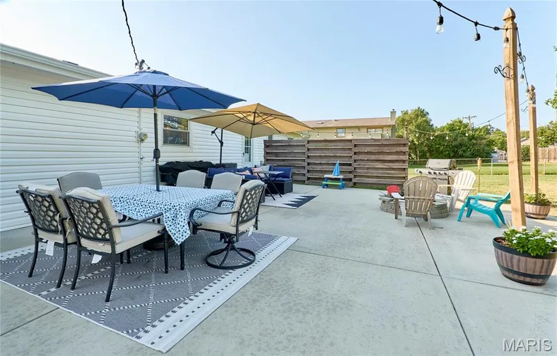 Expansive concrete patio with string lighting and a wood privacy fence — 415 Westridge Drive, O'Fallon, MO 63366
