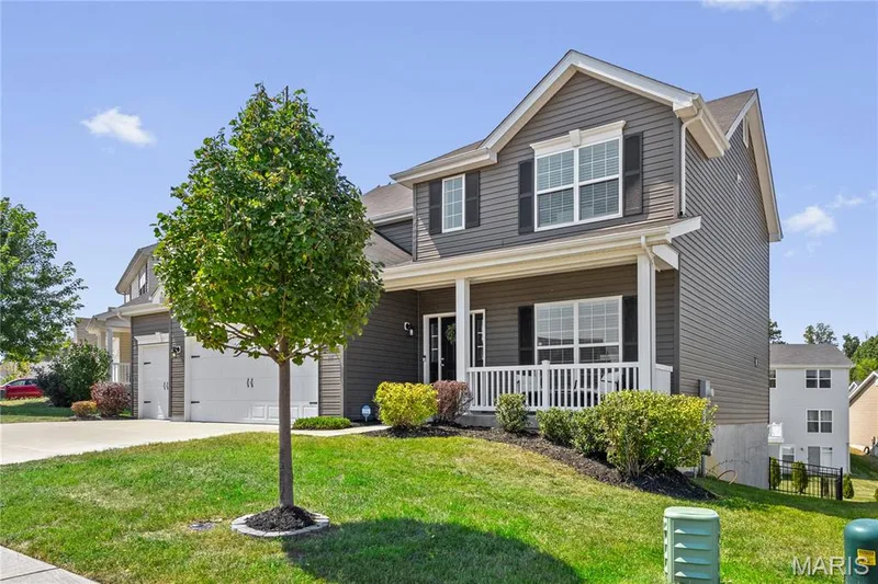 Two-story exterior with dark gray siding, white trim, a covered front porch, and an attached 3-car garage — 211 Brookview Way Court, O'Fallon, MO 63366