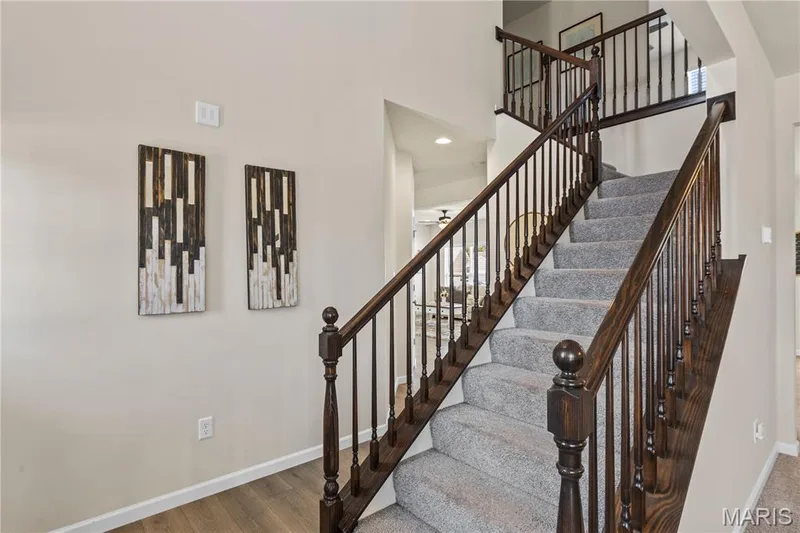 Carpeted staircase with dark wood-finish handrails and balusters, featuring a 2nd story landing with matching railings — 211 Brookview Way Court, O'Fallon, MO 63366
