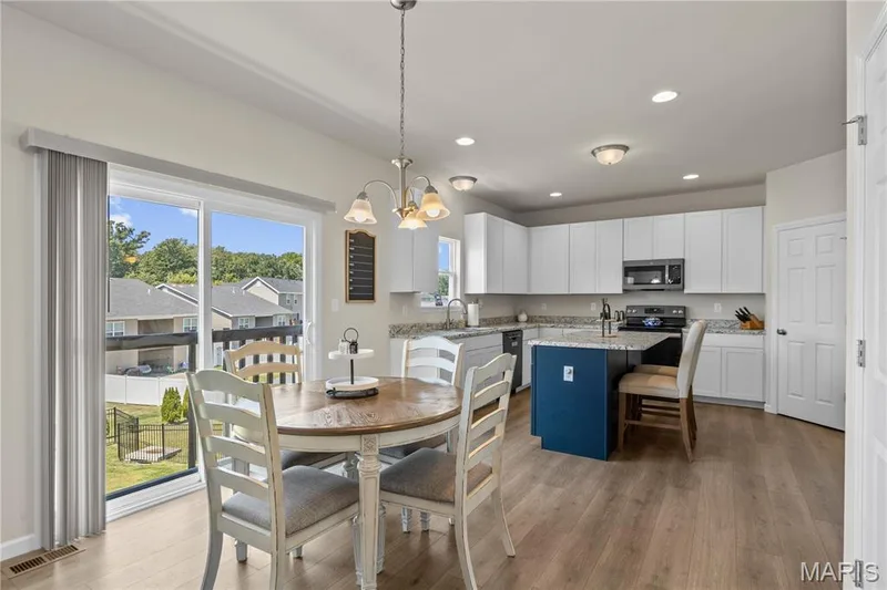 Kitchen featuring white cabinetry, laminate countertops, a central island with contrasting base cabinets, wood laminate flooring, and recessed lighting — 211 Brookview Way Court, O'Fallon, MO 63366