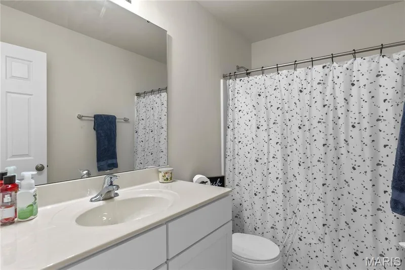 Single vanity with an integrated sink, polished chrome faucet, and expansive mirror — 211 Brookview Way Court, O'Fallon, MO 63366