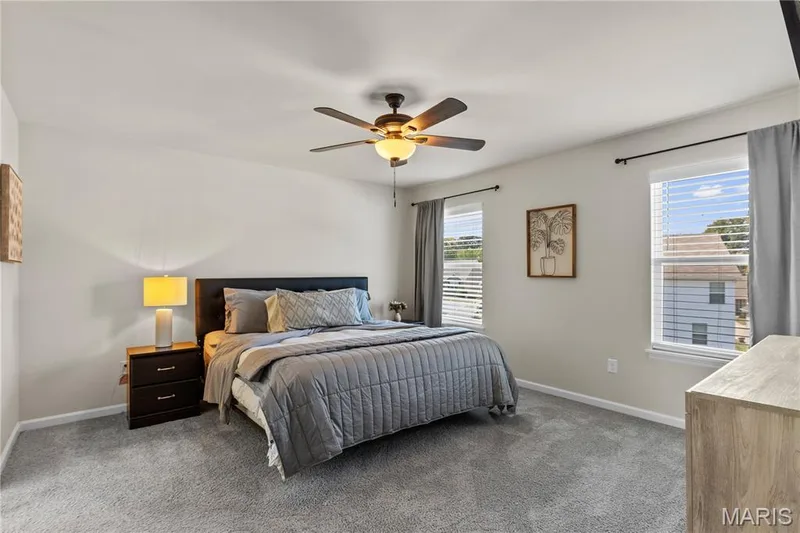 Carpeted flooring, two windows with blinds, ceiling fan with integrated lighting, and neutral wall tones — 211 Brookview Way Court, O'Fallon, MO 63366