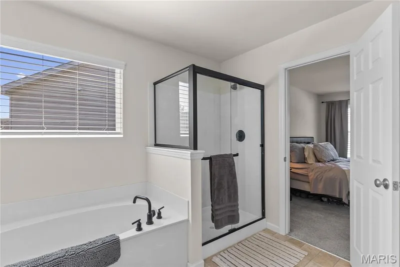 Built-in soaking tub with matte black fixtures, separate glass-enclosed shower with matte black frame, and vinyl flooring — 211 Brookview Way Court, O'Fallon, MO 63366