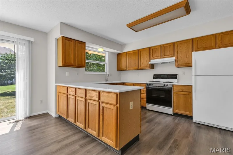 Kitchen features lots of wood cabinetry, gas stove, frig, new range hood and brand new quartz counter tops — 882 Sara Beth Court, St Peters, MO 63376