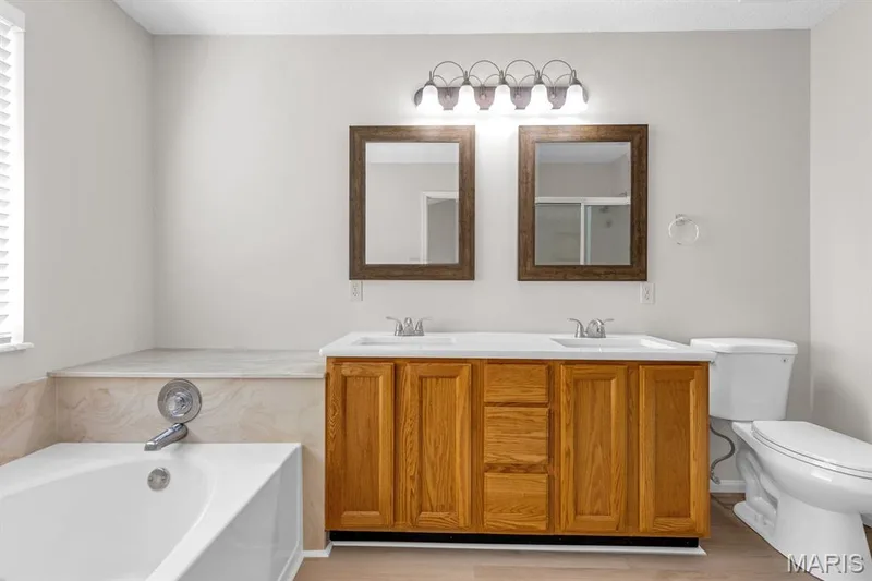 Primary Bathroom features new quartz countertop with new double bowl sinks, new mirrors & vinyl plank flooring — 882 Sara Beth Court, St Peters, MO 63376