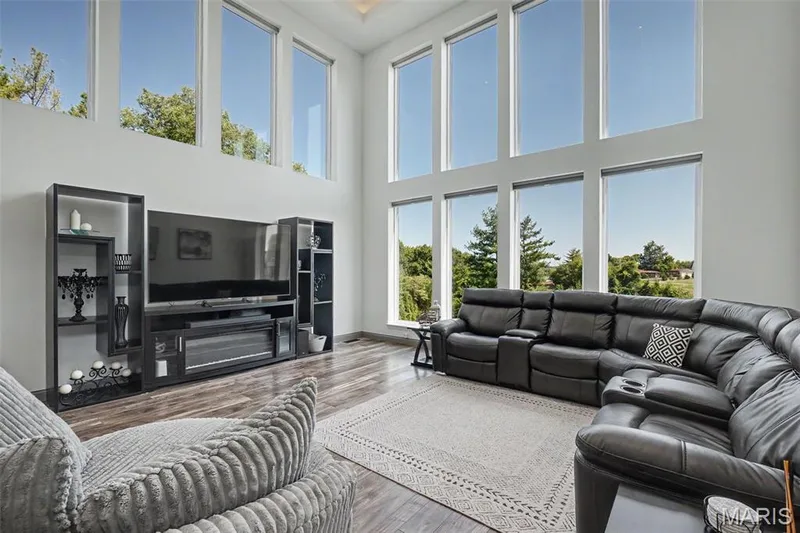 Double-height wall of windows, electric shades, sleek wood-finish flooring, and crisp white walls — 18 MacArthur Court, St Charles, MO 63304