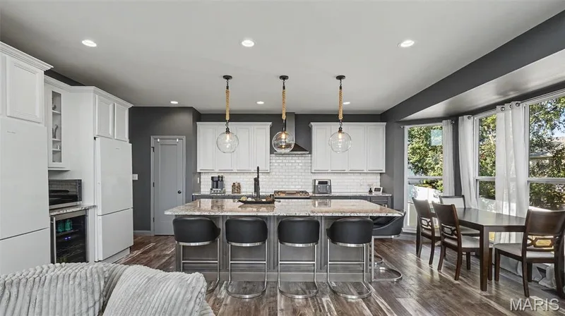 Kitchen featuring white shaker cabinetry, an expansive island with a stone countertop, recessed lighting, and wood-finish flooring — 18 MacArthur Court, St Charles, MO 63304