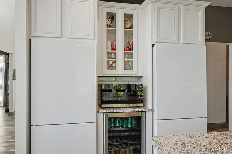 White paneled cabinetry with crown molding, glass-front display cabinet, subway tile backsplash, and a beverage cooler — 18 MacArthur Court, St Charles, MO 63304