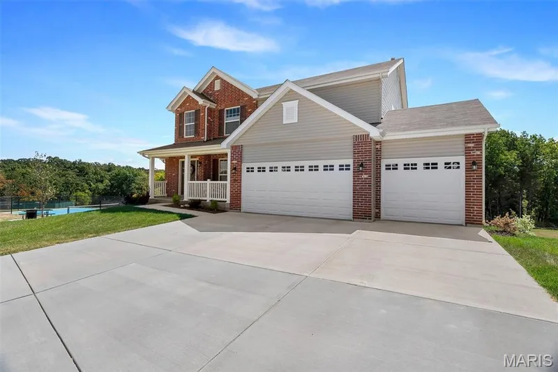 Brick and siding exterior with a covered porch, two dormer windows, and a multi-car garage — 337 White Orchid Court, Wentzville, MO 63385