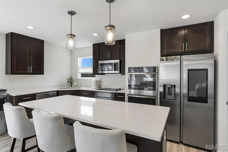 Kitchen featuring dark wood cabinetry, white countertops, stainless steel appliances, a large island, and recessed lighting — 337 White Orchid Court, Wentzville, MO 63385