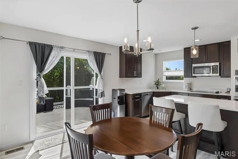 Open-concept kitchen with dark wood-finish cabinetry, stainless steel appliances, and a white countertop island — 337 White Orchid Court, Wentzville, MO 63385