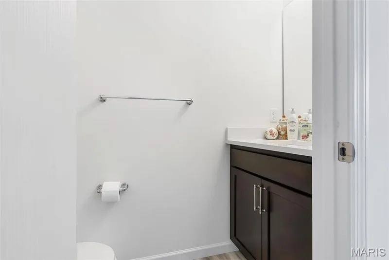 Dark wood-finish vanity with chrome hardware, white countertop, and wall-mounted mirror — 337 White Orchid Court, Wentzville, MO 63385
