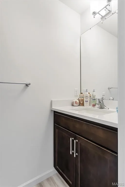 Dark wood-finish vanity with an integrated sink, white countertop, and a wall-mounted mirror — 337 White Orchid Court, Wentzville, MO 63385