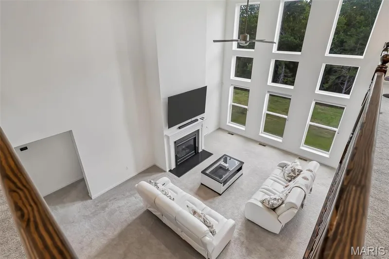 Two-story living area with a fireplace, ceiling fan, and multiple windows — 337 White Orchid Court, Wentzville, MO 63385
