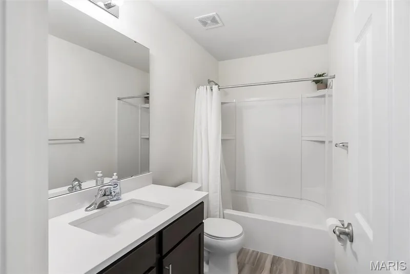 White vanity with integrated sink, dark wood-finish cabinetry, and chrome fixtures — 337 White Orchid Court, Wentzville, MO 63385