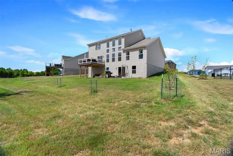 Expansive rear yard with a two-story beige siding exterior — 337 White Orchid Court, Wentzville, MO 63385