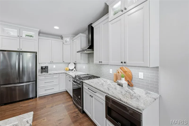 Stone countertops, stainless steel appliances, tile backsplash, and wood-finish flooring — 140 Oakleigh Park Lane, St Charles, MO 63303