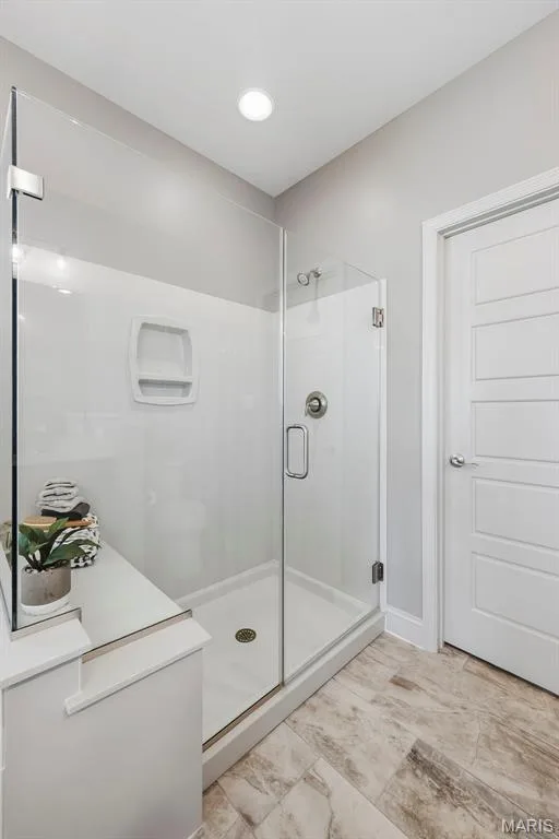 Glass-enclosed shower with built-in shelving and a bench, featuring a polished chrome shower system and a white shower pan — 140 Oakleigh Park Lane, St Charles, MO 63303
