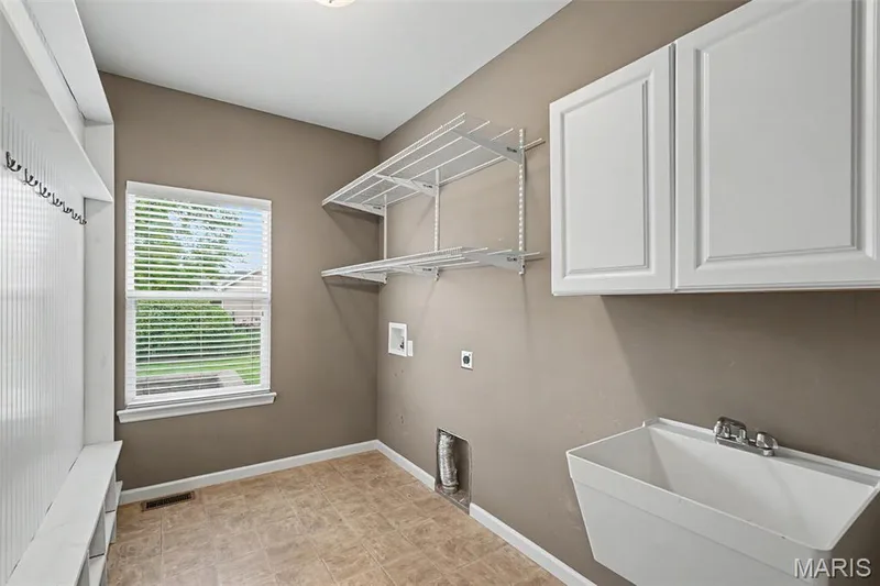 Main floor laundry with sink, cabinets, and cubby drop zone. — 152 Carlton Point Drive, Wentzville, MO 63385