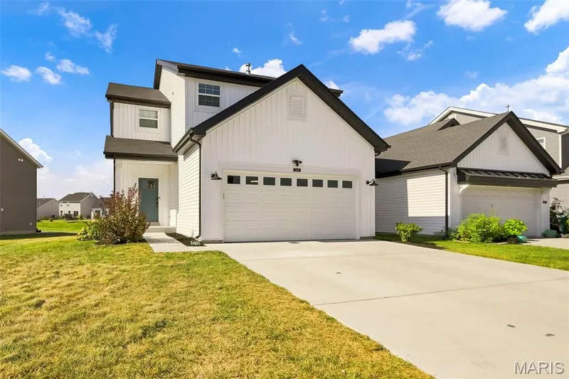 White vertical siding exterior with dark trim accents, a two-car garage, and a light-colored front door — 191 Crestfield Court, St Charles, MO 63301